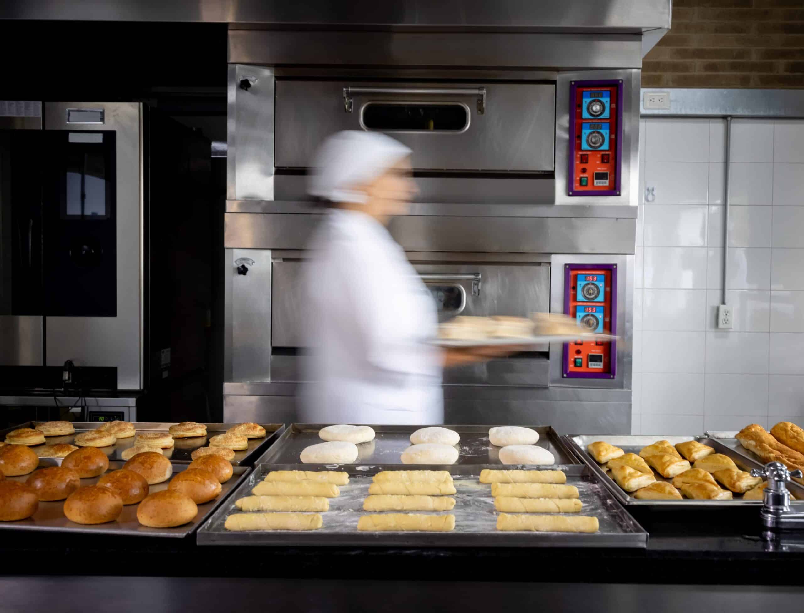 Blurred woman carrying tray in commercial kitchen