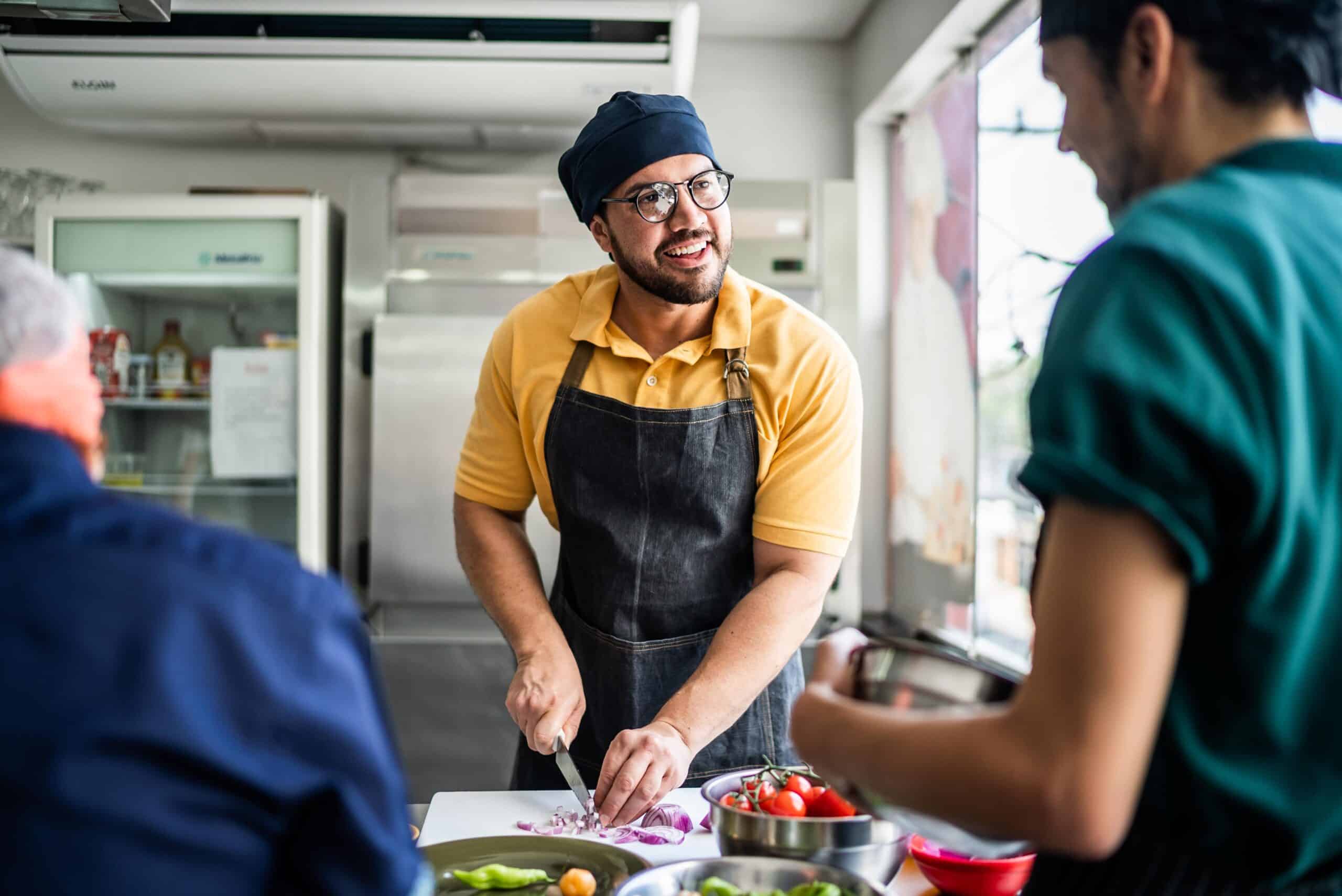 Man in yellow shirt chopping onions